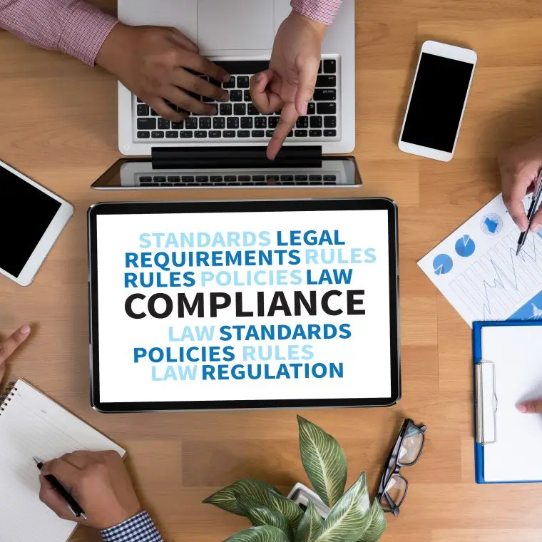 COMPLIANCE Business team hands at work with financial reports and a laptop, top view